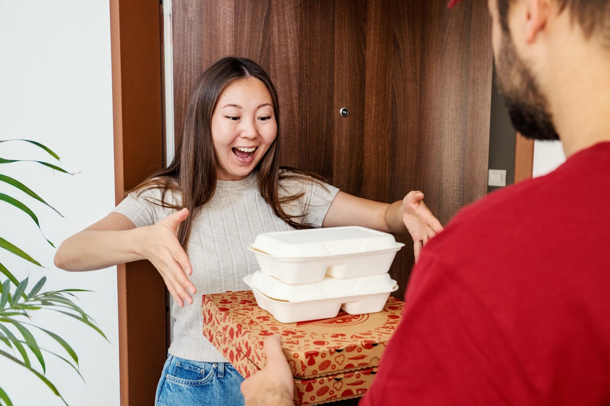 Entrega ao cliente no delivery: cliente recebendo o pedido do entregador na porta de casa