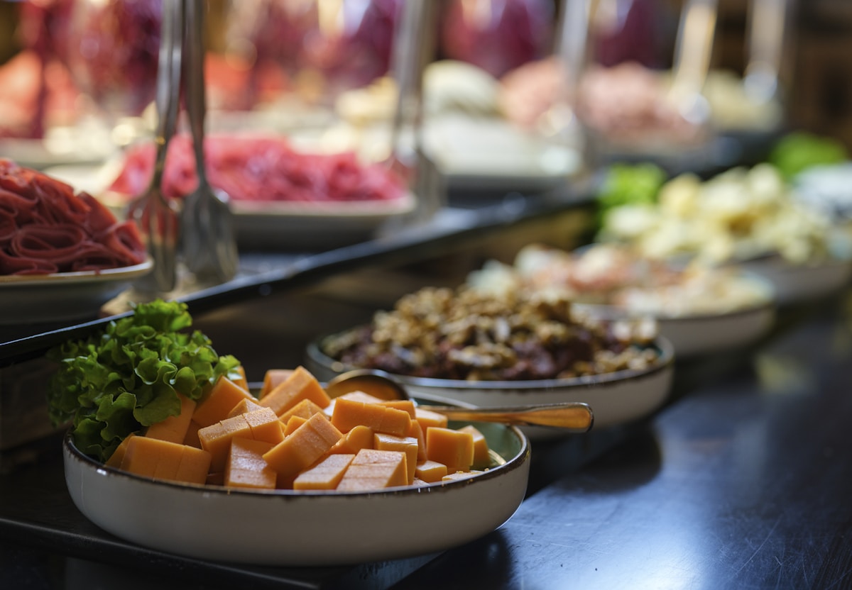 Buffet de restaurante self service com cubas de saladas e pegadores sobre a rampa
